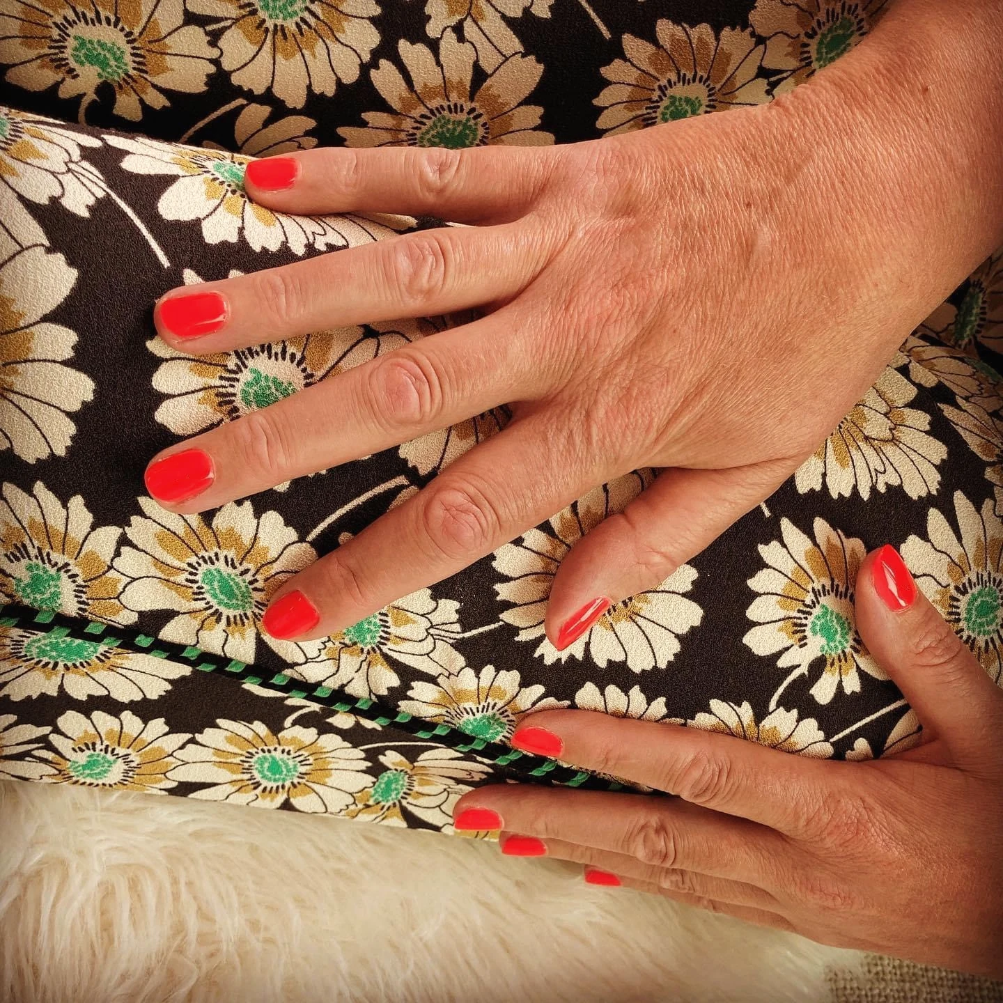 Manicure met helderrode nagellak op bloemenprint